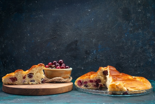 Frotn view deliciosa torta de cereja fatiada junto com ginjas vermelhas no escuro