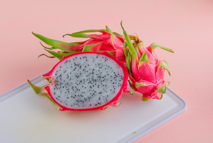 Foto grátis fruta do dragão na placa-de-rosa e de corte. vista de alto ângulo.