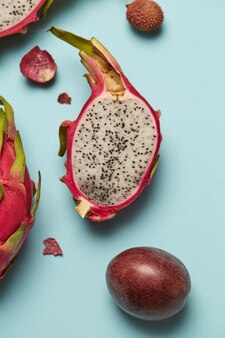 Fruta do dragão rosa exótica metade sobre fundo azul com maracujá. fruta tropical doce, corte suculento de pitaya