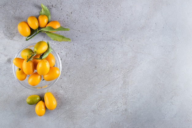Frutas cítricas inteiras frescas de cumquat com folhas colocadas em uma tigela Foto Premium