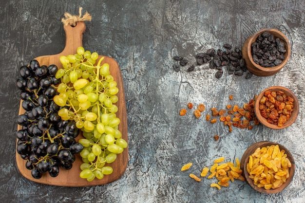 Frutas coloridas frutas secas verdes e uvas pretas na tábua