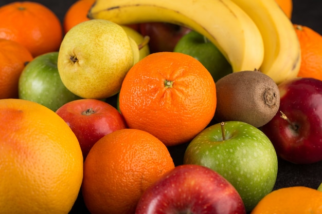 Frutas coloridas maduras maduras laranjas e maçãs na mesa escura