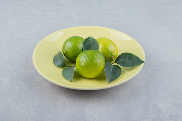 Frutas deliciosas de limão com folhas na placa amarela.