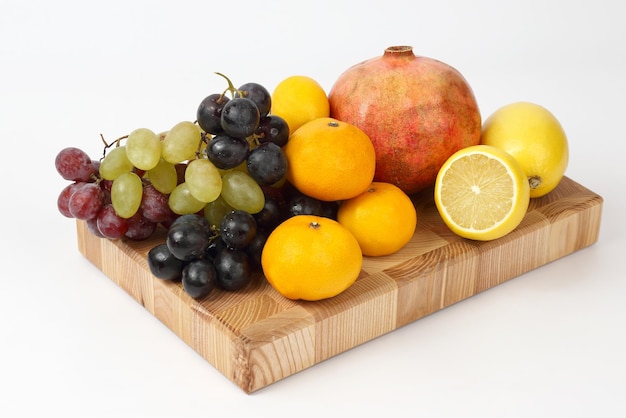 Frutas diferentes em uma placa de madeira em um fundo branco