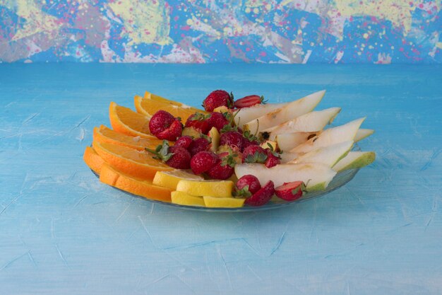 Frutas fatiadas em uma travessa de vidro isolada no espaço azul