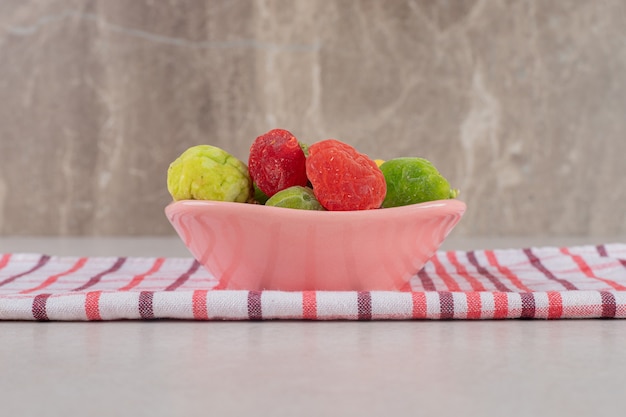 Frutas secas coloridas em uma xícara rosa.