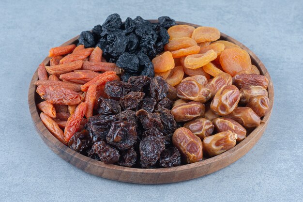 Frutas secas na tábua de madeira, sobre a mesa de mármore.