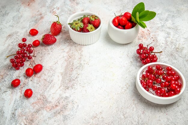 Frutas vermelhas de vista frontal com frutas vermelhas na mesa branca