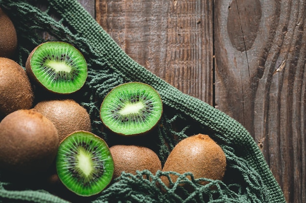 Foto grátis frutos de kiwi em um saco de malha em um estilo rústico de vista superior de fundo de madeira