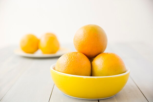 Frutos inteiros laranjas na tigela na mesa de madeira