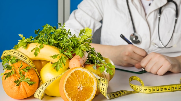 Frutos saudáveis ​​frescos com fita métrica na mesa da nutricionista