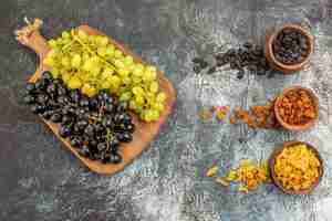 Foto grátis frutos secos cachos de uvas verdes e pretas no tabuleiro e frutos secos