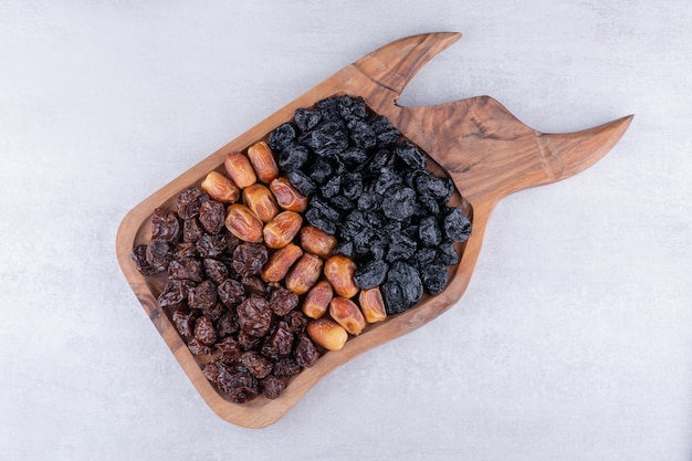 Frutos secos com tâmaras e cerejas numa travessa de madeira. Foto de alta qualidade