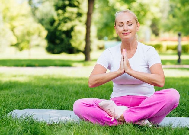 Full shot mulher feliz meditando ao ar livre