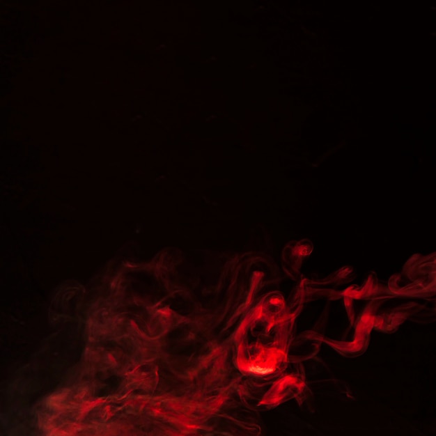 Fumaça vermelha escura soprando contra o fundo escuro