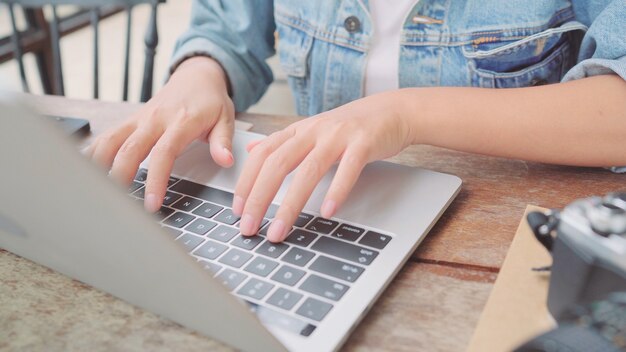 Funcionamento asiático autônomo da mulher do negócio, fazendo projetos e enviando o email no portátil ou no computador ao sentar-se na tabela no café. Mulheres bonitas espertas do estilo de vida que trabalham em conceitos da cafetaria.