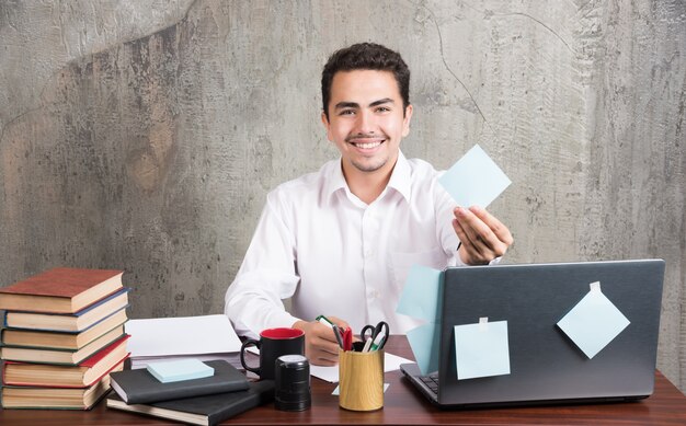 Funcionário do escritório mostrando alegremente seu bloco de notas na mesa do escritório.