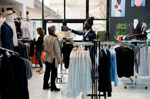 Funcionário do showroom ajudando a mulher sênior a escolher a bolsa, comprando roupas casuais na boutique moderna. Cliente idoso comprando mercadorias da moda e acessórios da moda. conceito de moda