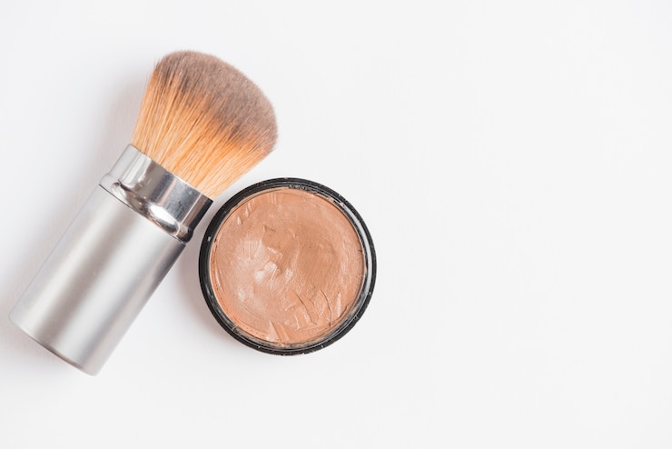 Foto grátis fundação de creme com pincel em pano de fundo branco