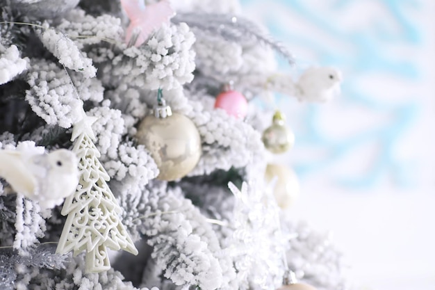 Fundo de férias de natal. bugiganga de prata e cor pendurada em uma árvore decorada com bokeh e neve, copie o espaço.