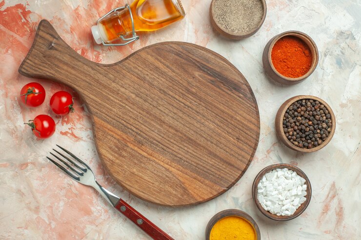 Foto grátis fundo de jantar com tomates em um prato branco em uma tábua de madeira e uma garrafa de óleo com uma faca de especiarias diferentes caídas em um fundo de cor mista