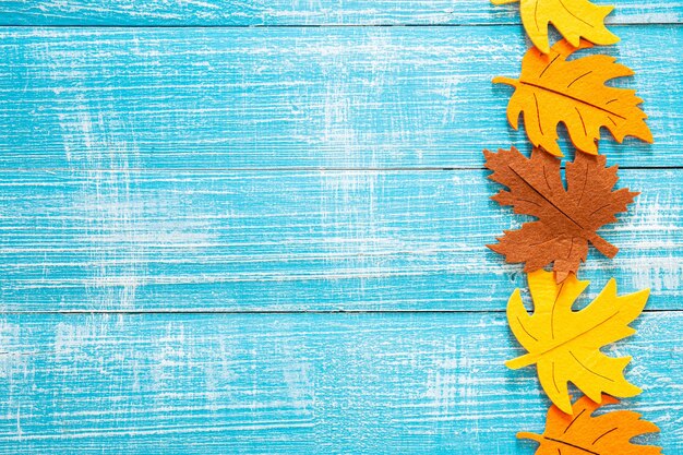 Fundo de madeira de outono com folhas de feltro coloridas