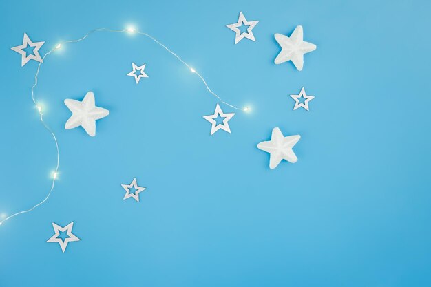 Fundo de Natal azul com guirlanda e estrelas decorativas planas