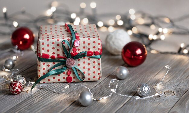 Fundo de Natal com caixa de presente close-up na superfície de madeira, bolas de Natal e luzes de bokeh, copie o espaço.