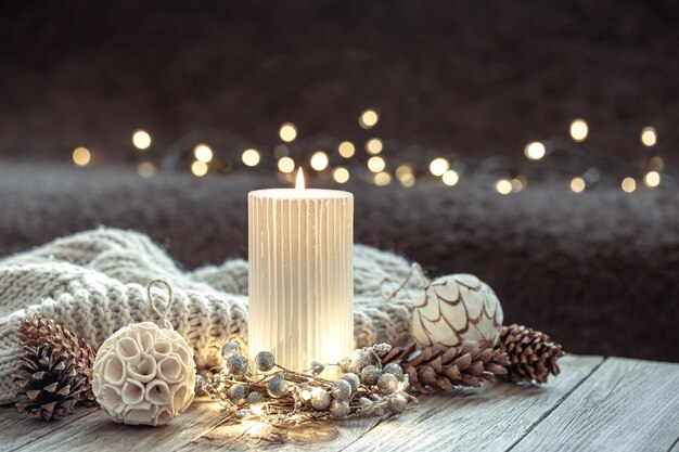 Fundo festivo de inverno com vela acesa e detalhes de decoração para casa no fundo desfocado com bokeh.