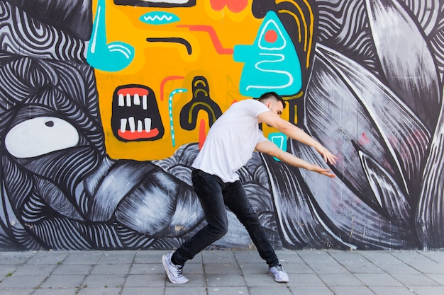 Foto grátis funil de quadril realizando dança na frente da parede de graffiti