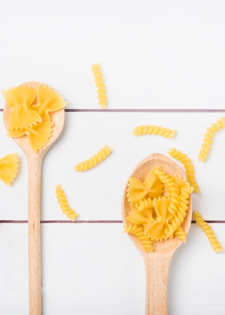 Foto grátis fusilli de macarrão cru e farfalle na colher de pau