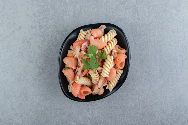 Fusilli e massa de concha vermelha em tigela preta.