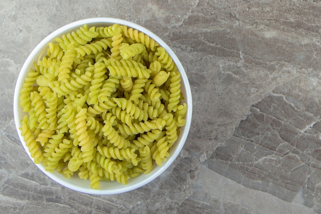 Fusilli verde cru em uma tigela branca.