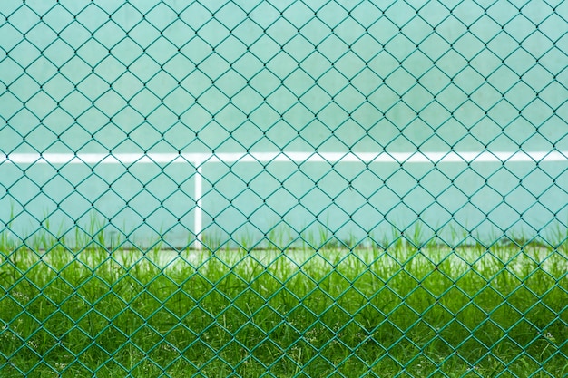 Gaiola de metal verde frente a quadra de tênis verde e parede para prática