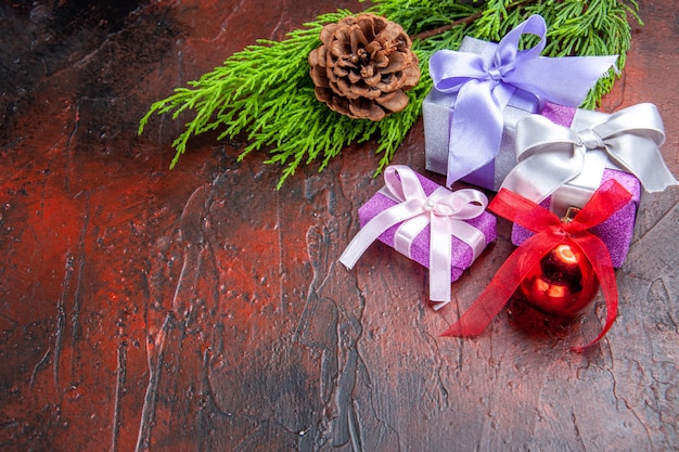 Galho de árvore de presentes de natal com cone de brinquedo de árvore de natal em fundo vermelho escuro cópia espaço foto de ano novo vista inferior