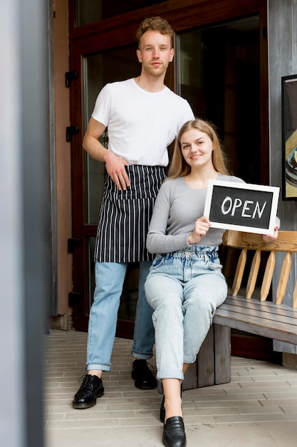 Foto grátis garçom masculino e mulher com sinal aberto para café