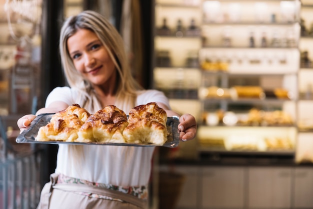 Garçonete oferecendo bandeja de croissant