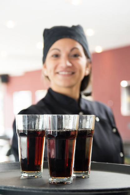 Garçonete sorridente segurando copos de bebidas alcoólicas