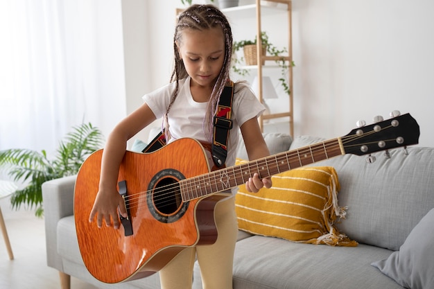 Garota adorável tocando violão em casa