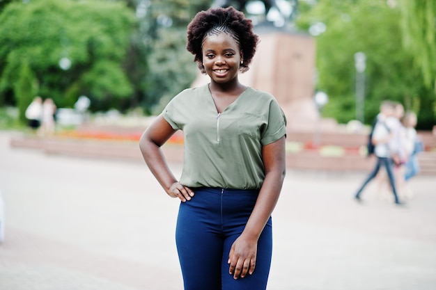 Garota africana posou na rua da cidade vestindo blusa verde e calça azul