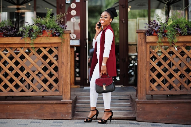 Garota afro-americana com bolsa de mão posou ao ar livre da cidade de steets e falando ao telefone