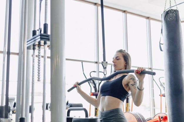 Garota atlética atraente treina ombros no simulador. vista dos músculos das costas. estilo de vida saudável.