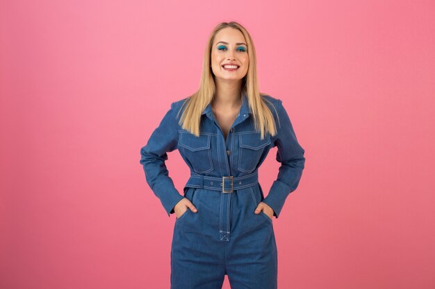 Garota atraente animada posando em um fundo rosa em uma tendência geral da moda de jeans