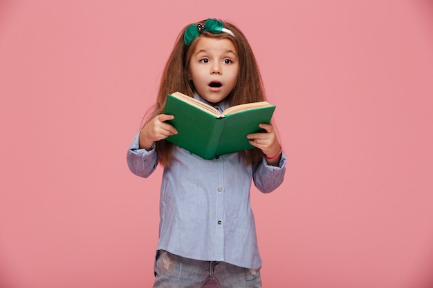 Garota atraente com aparência europeia, segurando o livro nas mãos, expressando interesse e curiosidade