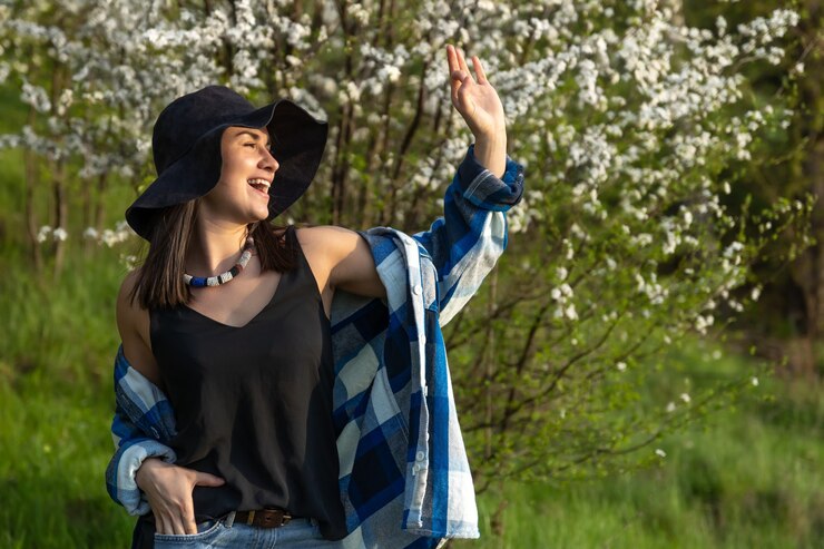 Foto grátis garota atraente com um chapéu entre as árvores floridas na primavera, em um estilo casual