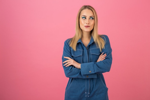 Garota atraente posando em fundo rosa em uma tendência geral da moda de jeans