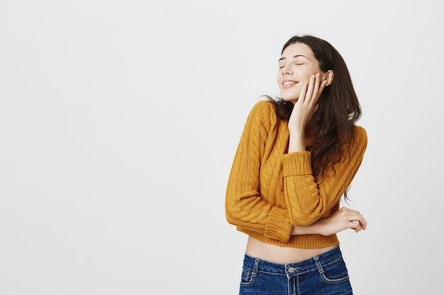 Foto grátis garota atraente romântica sonhando acordada, olhos fechados e sorrindo feliz