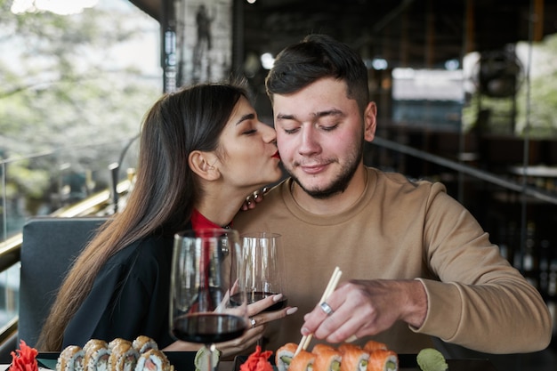 Garota beija um cara na bochecha em um restaurante japonês