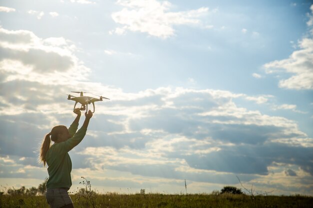 garota bonita em um campo lança o drone no céu