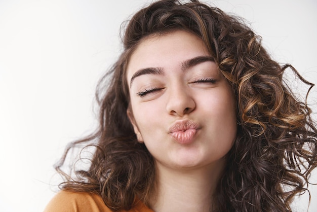 garota cabelo preto cacheado dobrando os lábios fechando os olhos esperando o príncipe encantado beijá-la enviando adorável mwah sentir romântico